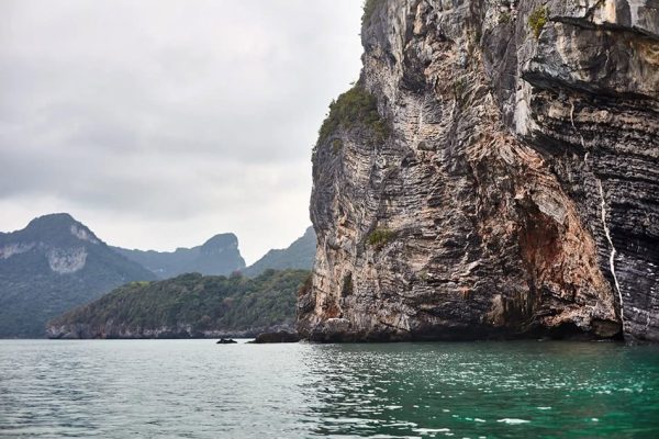 Scenic view of water and a cliff in Ang Thong, reflecting Arex's team composition. Extensive backgrounds in senior global roles and projects from small to medium-sized enterprises